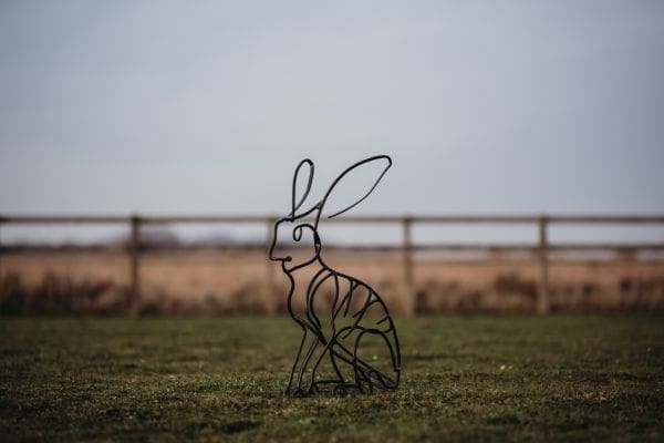Steel hare sculpture by Ollie Holman showing a seated hare upright and alert.