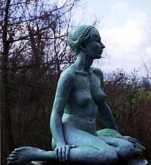 Life-size resin sculpture “Lucie” of a seated woman by Heather Burnley.