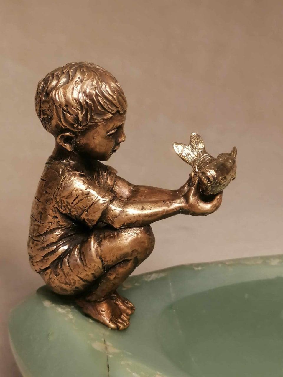 Bronze sculpture of a boy with a golden fish by Anna Tölgyesi Poós