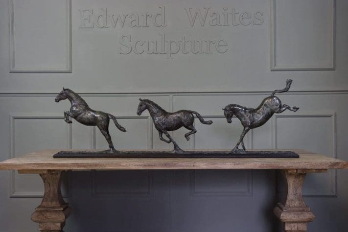 Bronze sculpture of three horses by Edward Waites in dynamic movement.