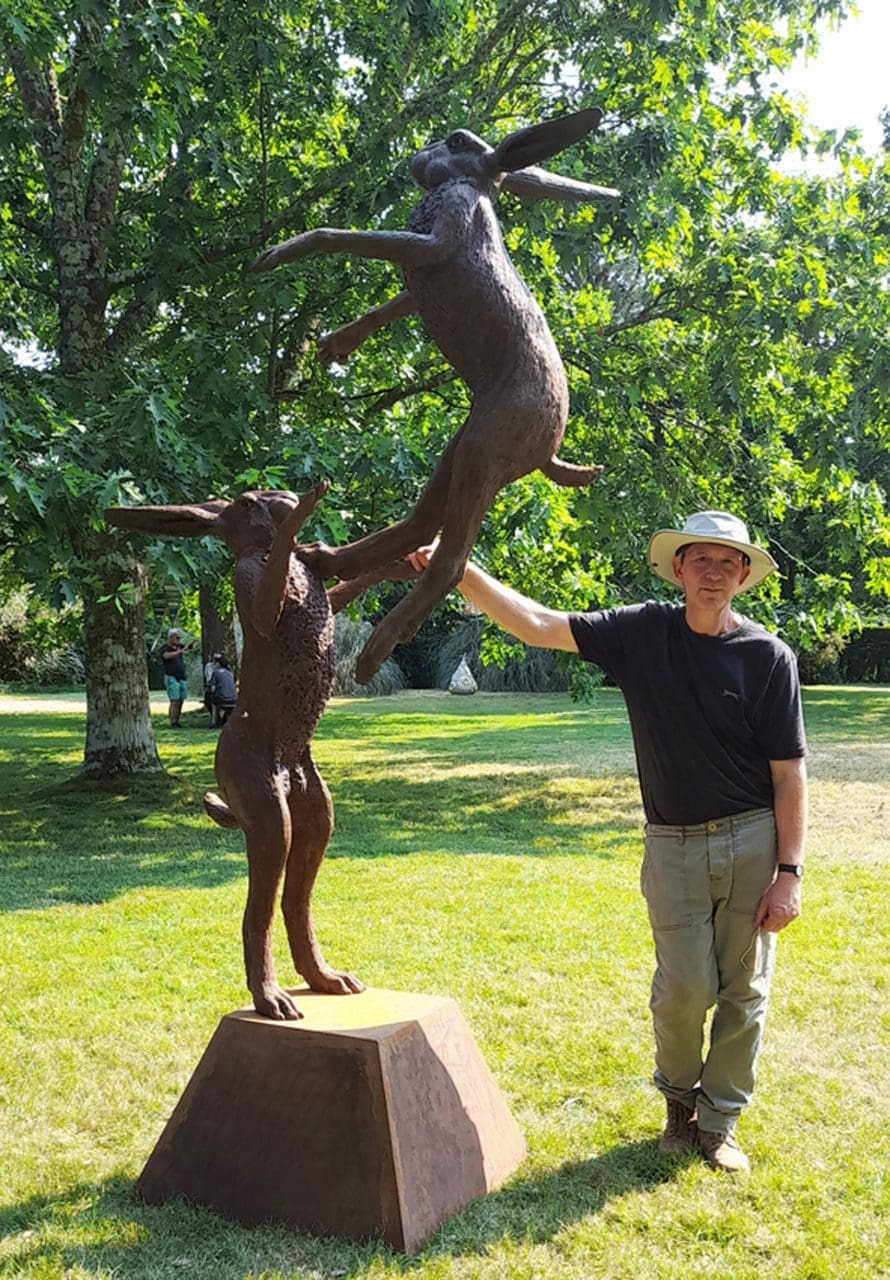 Martin Duffy standing beside Large Leaping Boxing Hares monumental iron resin sculpture